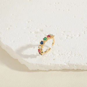 Detail of adjustable gold ring with multi-colored cubic zirconia stones on white stone