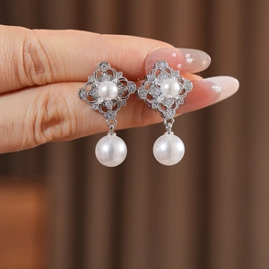 Macro detail of vintage hollow diamond-shaped earrings with pearls and pavé cubic zirconia
