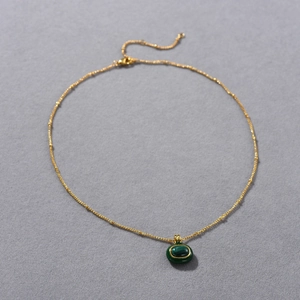 Detail showing an 18k gold plated necklace with an oval green malachite gemstone pendant
