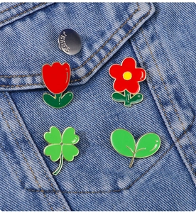 Détail de broches en émail en forme de plantes sur la poche d'une veste en jean bleue
