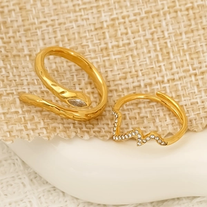 Goldenes Schlangenring-Set mit Zirkonia-Blitzring auf beigem Webhintergrund