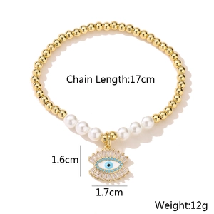 Detail of 18K gold-plated evil eye charm on beaded bracelet with white pearls