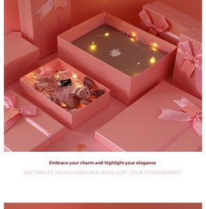 Detailed view of pink gift boxes with satin ribbons, shredded paper, and LED fairy lights
