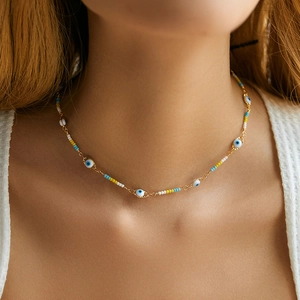 Detail view of Bohemian evil eye beaded necklace with blue and white beads on a gold chain