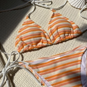 Dettaglio del bikini in spugna a righe con texture arancioni su sfondo lavorato a maglia