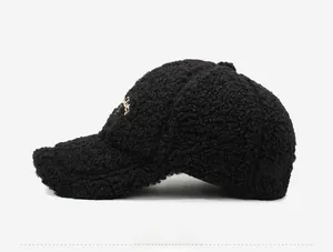Close-up of black teddy fleece baseball cap featuring detailed gold letter embroidery