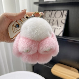 Close-up of a pink and white fluffy bunny keychain attached to a BMW car key