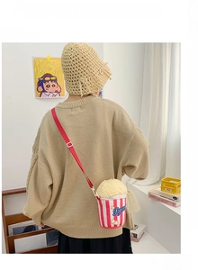 Detail of cute popcorn-shaped plush crossbody bag with red stripes and fluffy texture