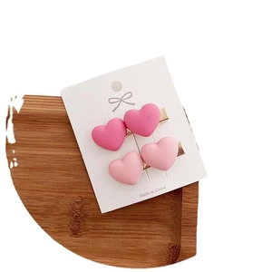 Pink heart hair clips set with sweet bow design on a white display card stand