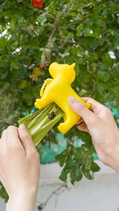 Close-up of dog-shaped waste bag dispenser with green bags and carabiner in nature