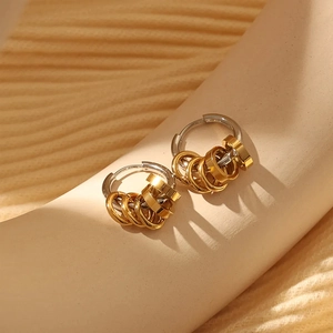 Macro shot of two-tone stainless steel earrings with five gold charms on silver hoops
