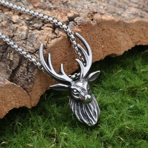 Vintage stainless steel sika deer pendant necklace on natural moss and bark backdrop