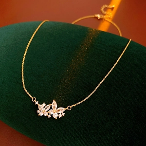 Détail d'un collier papillon doré avec pierres blanches sur un support velours