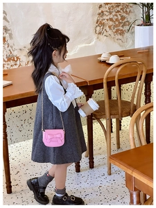 Girl in grey wool dress carrying a pink mini bow crossbody bag with chain strap