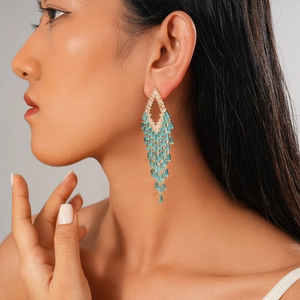 Close-up of long gold tassel earrings with light blue crystals worn by a model