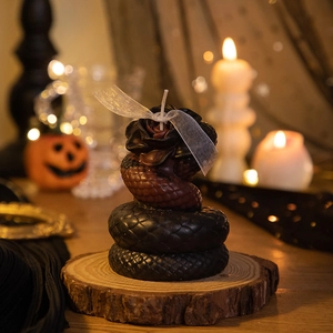 Detail of snake-shaped Halloween candle with rose top on a rustic wooden base