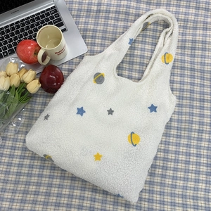 Close-up of white plush tote bag with star embroidery on a checkered background