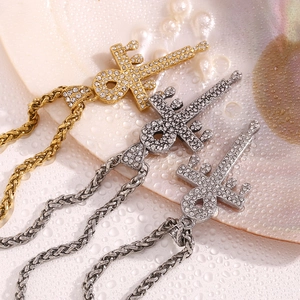 Detail of crystal paved sword cross pendants on braided rope chains in gold and silver