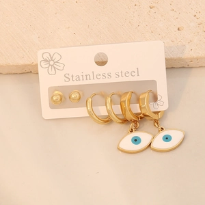 Close-up of gold stainless steel earring set with blue evil eye charms on stone surface