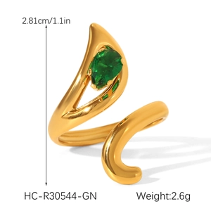 Detail shot of a golden spiral ring featuring a green teardrop zircon and high-polish finish