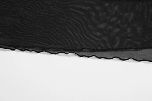 Detail view of the lettuce edge hem on black sheer mesh V-neck dress fabric