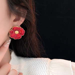 Close-up of vintage red enamel flower earring with gold-edged petals on a model