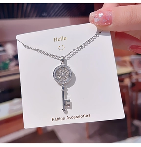 Detailed view of silver key pendant necklace with zircon inlays and hollow sunburst design