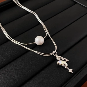 Detail of silver double layer necklace with pearl and moon star pendant on black box