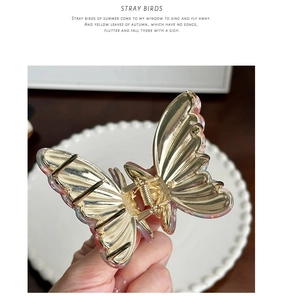 Macro detail of butterfly hair claw clip with golden metal and pink resin butterfly wings
