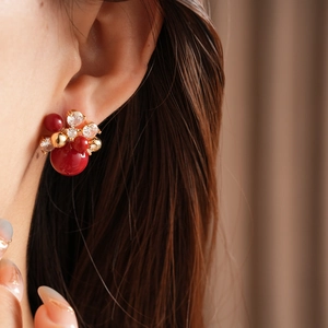 Macro shot of red bead cluster earrings with sparkling zircons and gold plating