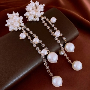 Gros plan de boucles d'oreilles fleurs en perles et pampilles avec chaînes dorées