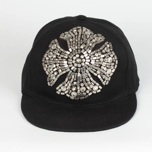 Detail of metal studs and rhinestones forming a cross pattern on a flat brim baseball cap