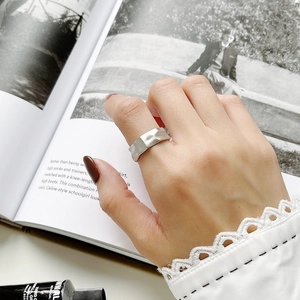 Detail of matte silver open ring with irregular hammered texture on female index finger