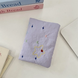 Detail of lavender fabric passport holder with embroidered stars and crescent moon patterns