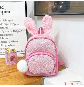 Detailed view of pink sequin kids backpack with cute rabbit ears and white pompom charm