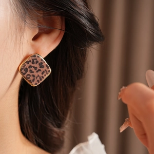 Gros plan d'une boucle d'oreille dorée carrée à motif léopard portée par un mannequin
