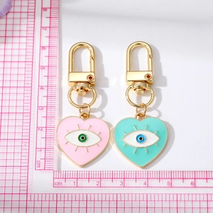 Detail of pink and mint heart-shaped evil eye keychains with gold hook and measurement scale