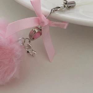 Detailed close-up of a pink plush pompom keychain with a silky ribbon bow and star charm