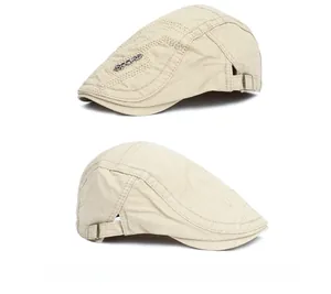 Close-up of beige vintage flat cap featuring side metal sports logo and adjustable buckle