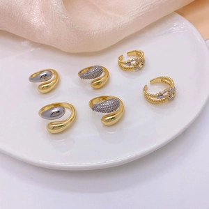 Gold and silver horseshoe rings with zircon inlay on a white plate and beige silk