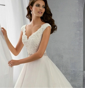 Détail de robe de mariée en dentelle à col en V avec ceinture à paillettes et jupe en tulle
