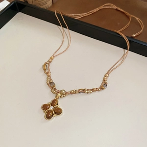 Macro shot of tiger eye stone flower pendant necklace with vintage golden beaded chain
