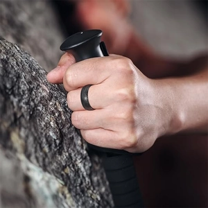 Rugged black Damascus patterned titanium ring for men shown on hand in outdoor setting
