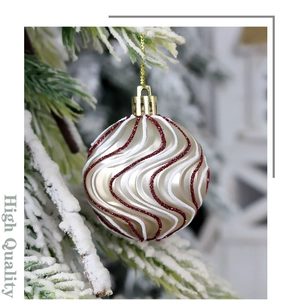 Detail of red glitter wave patterns on a shiny gold Christmas ball hanging on a snowy tree