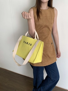 Detail of yellow straw tote bag with long straps and PARIS embroidery for beach vacation