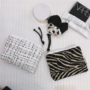 Detail showing tweed and zebra pattern mini zipper coin purses with cosmetics