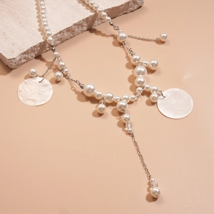 Chic pearl and shell pendant necklace with tassel detail on a textured stone background