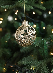 Dettaglio di una pallina di Natale dorata a spirale con finitura lucida su un ramo di pino