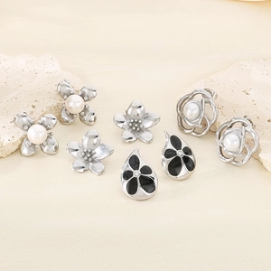 Flat lay of vintage style floral earrings with pearls and black enamel on natural stone