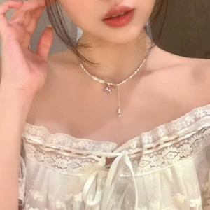 Dettaglio ravvicinato di un'elegante collana con farfalla e ciondolo a goccia d'acqua.
